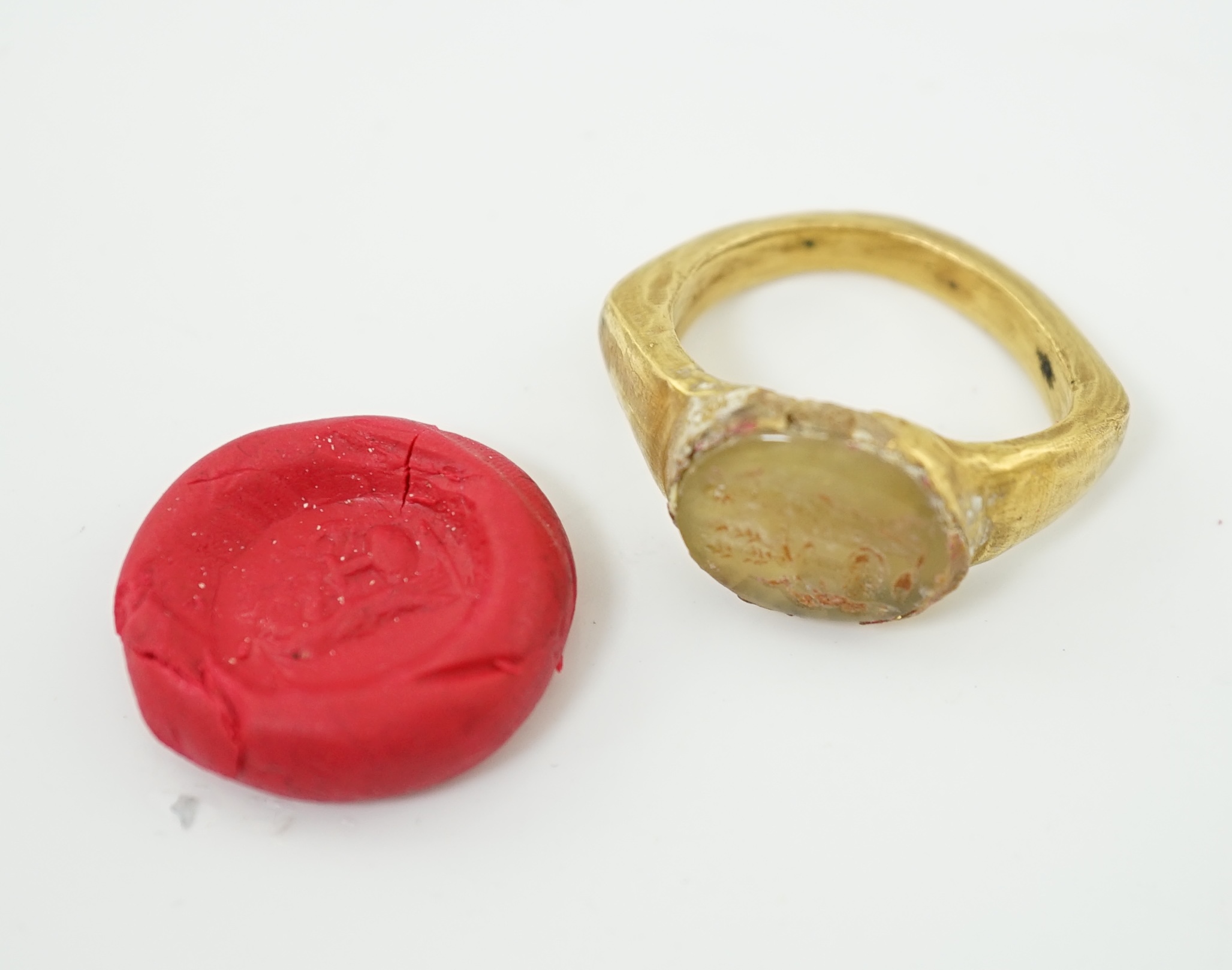 A Roman gold and hardstone intaglio military finger ring, carved with Saturn beside a pedestal